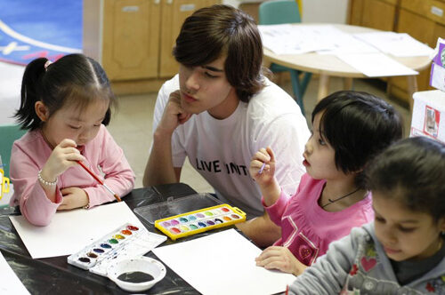 Youth volunteer w kids in day care or school